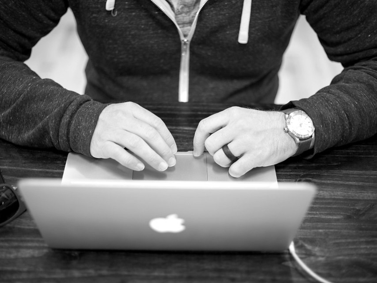 Hands typing on a laptop, a watch on the wrist